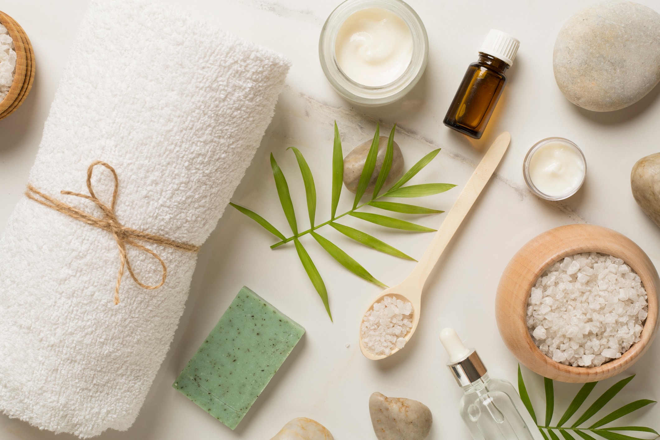 Spa skincare flatlay — towel, sea salt, essential oils, and natural exfoliating products